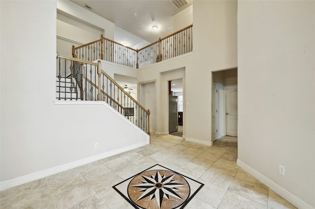 foyer entrance featuring visible vents, a towering ceiling, stairway, tile patterned flooring, and baseboards