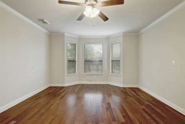 empty room featuring ornamental molding, visible vents, baseboards, and wood finished floors