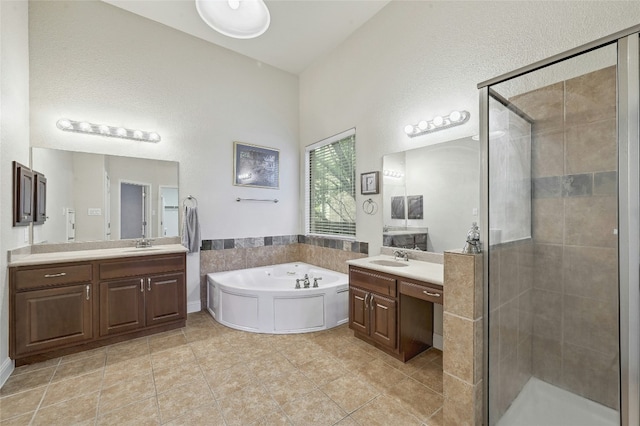 full bathroom featuring a stall shower, two vanities, a garden tub, and a sink