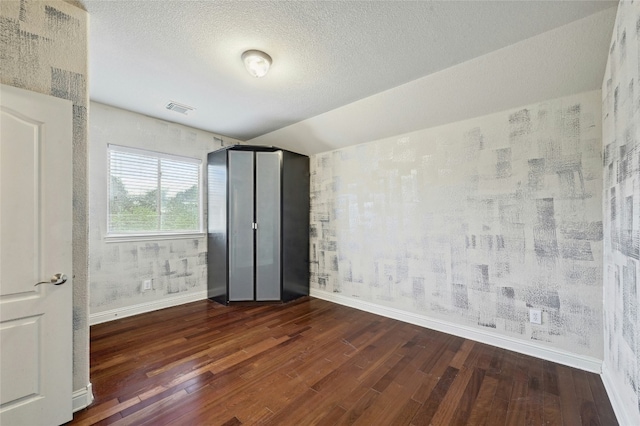 unfurnished bedroom with visible vents, a textured ceiling, baseboards, and wood finished floors