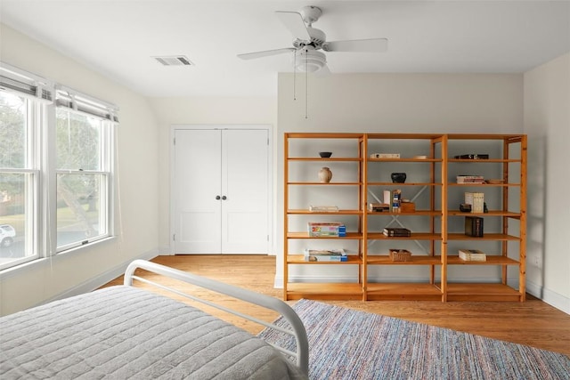 bedroom featuring baseboards, visible vents, ceiling fan, wood finished floors, and a closet