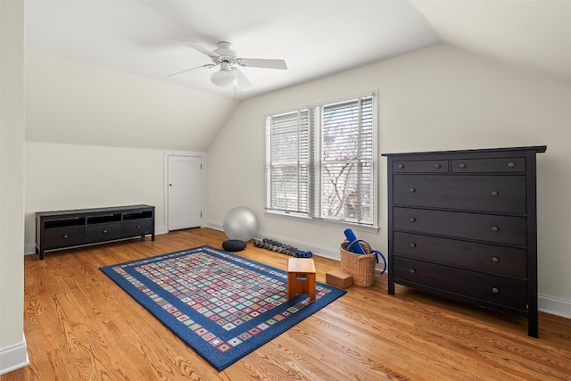 workout room featuring lofted ceiling, ceiling fan, wood finished floors, and baseboards