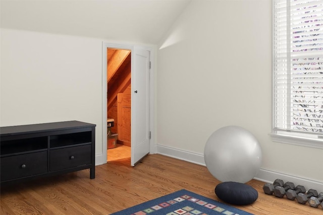 workout room with vaulted ceiling, baseboards, and wood finished floors