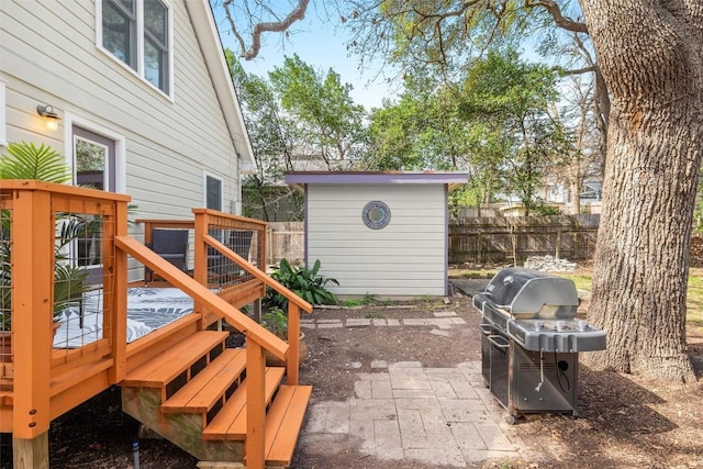 exterior space featuring an outbuilding, fence, a grill, a wooden deck, and a storage unit