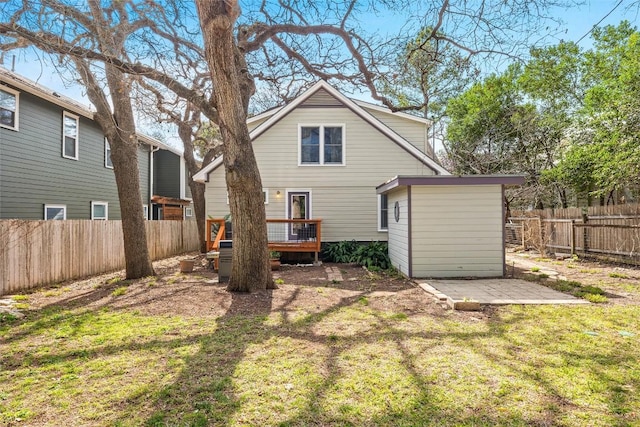 back of house featuring a fenced backyard, a deck, a yard, a shed, and an outdoor structure