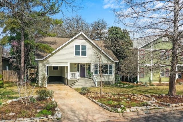 bungalow-style home with covered porch, driveway, a shingled roof, and a front yard