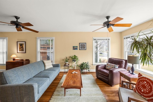 living room featuring ceiling fan, baseboards, and wood finished floors