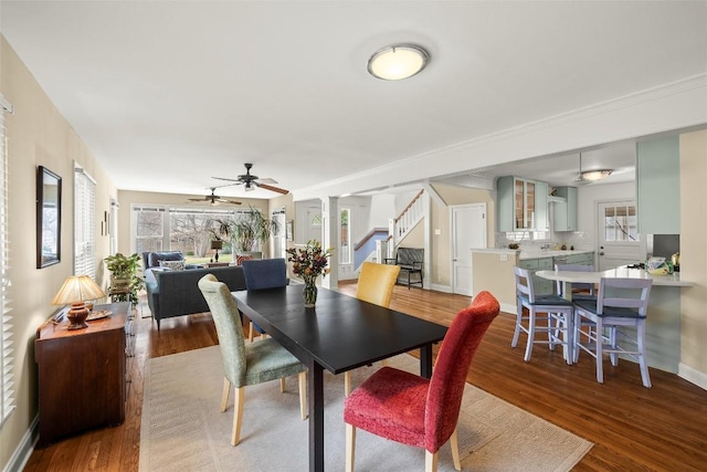 dining space featuring baseboards, wood finished floors, stairs, and ceiling fan