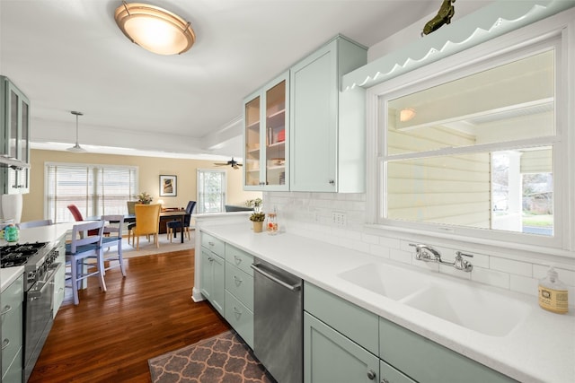 kitchen with dark wood-style flooring, light countertops, decorative backsplash, appliances with stainless steel finishes, and a sink