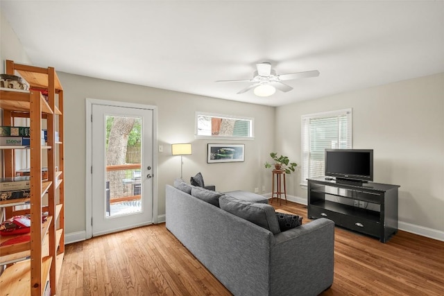 living area featuring baseboards, a ceiling fan, and wood finished floors