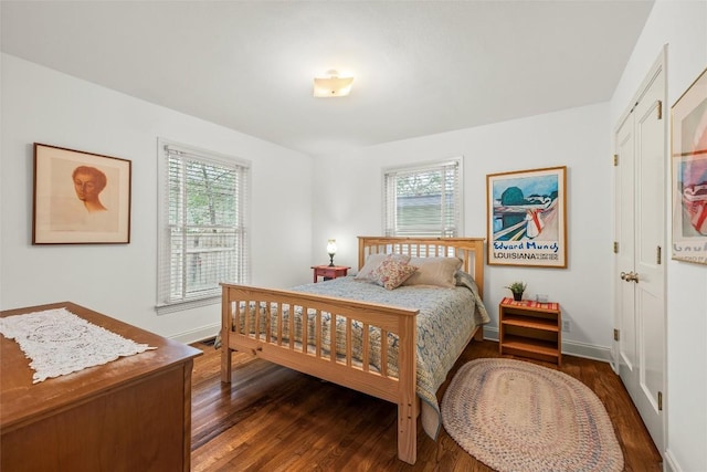 bedroom with multiple windows, baseboards, and wood finished floors