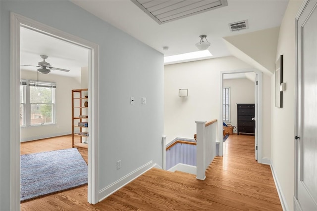 hallway featuring lofted ceiling, an upstairs landing, visible vents, and light wood-style floors