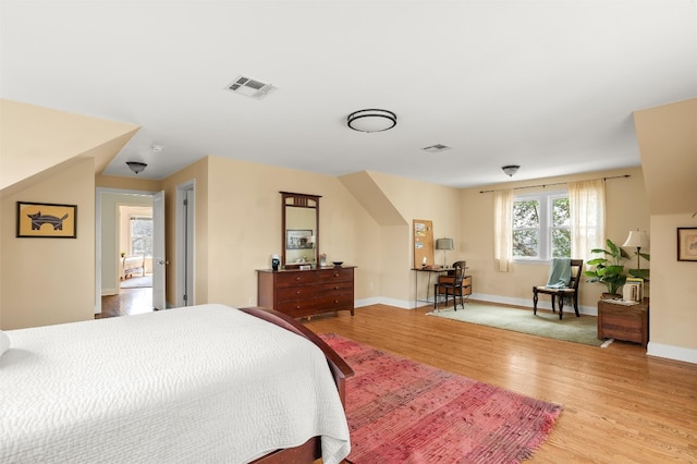 bedroom featuring light wood-style floors, visible vents, and baseboards