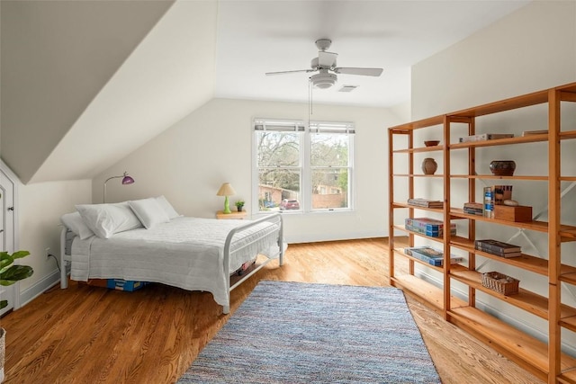 bedroom featuring a ceiling fan, wood finished floors, baseboards, lofted ceiling, and visible vents