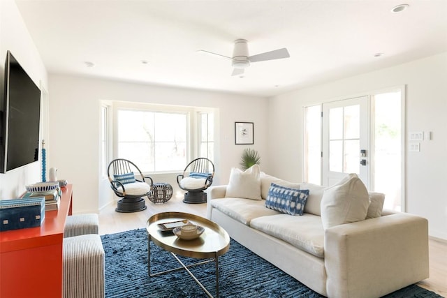 living area with ceiling fan, plenty of natural light, and wood finished floors