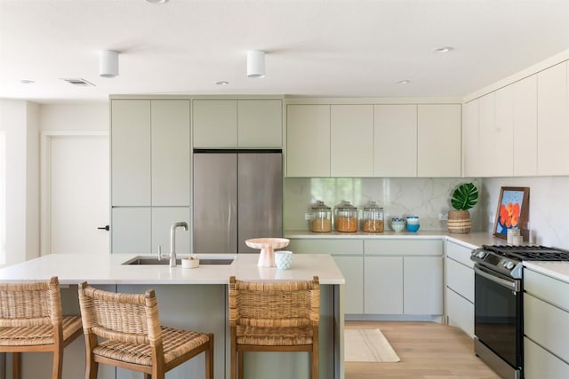 kitchen featuring appliances with stainless steel finishes, decorative backsplash, a sink, and light countertops