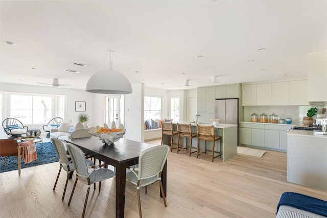 dining space with light wood-type flooring, visible vents, and plenty of natural light