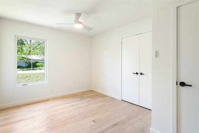 unfurnished bedroom featuring light wood-type flooring, ceiling fan, baseboards, and a closet