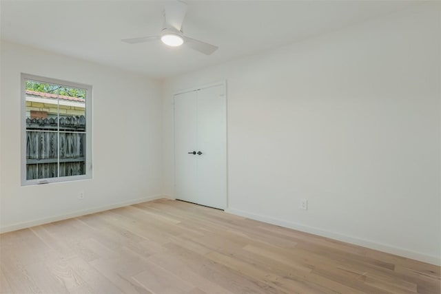 spare room featuring a ceiling fan, light wood-style flooring, and baseboards