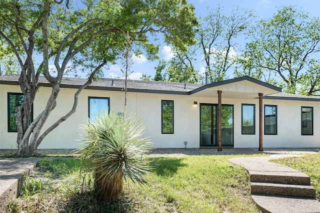 back of property featuring a yard and stucco siding