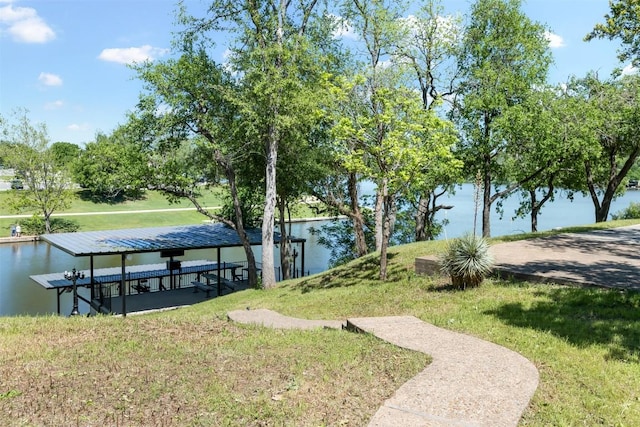 view of property's community featuring a dock, a water view, and a lawn