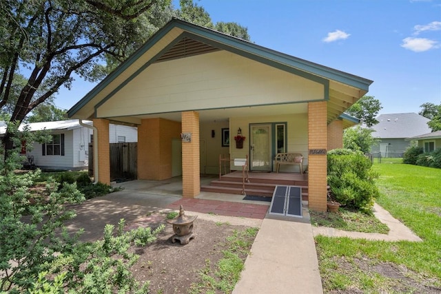 back of house featuring fence, a porch, a lawn, and brick siding