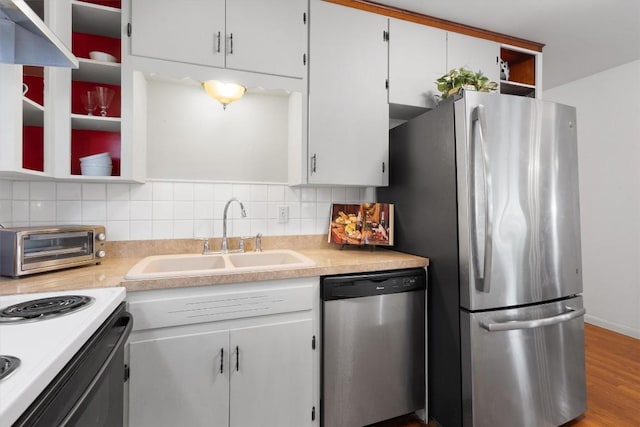 kitchen featuring tasteful backsplash, appliances with stainless steel finishes, wood finished floors, light countertops, and a sink