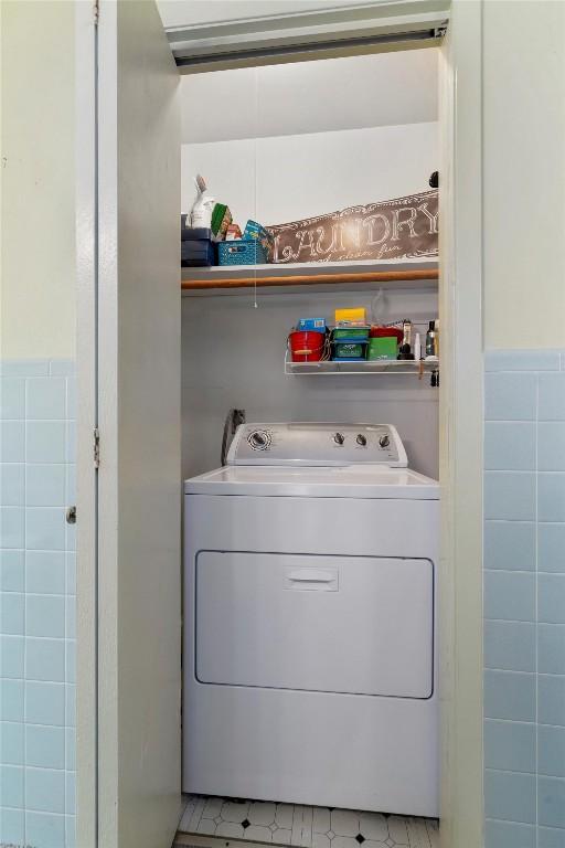 washroom featuring a wainscoted wall, washer / clothes dryer, and tile walls