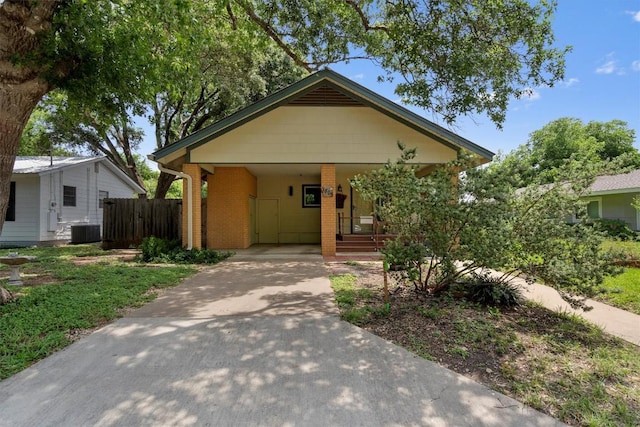 bungalow featuring driveway, brick siding, central AC unit, and fence