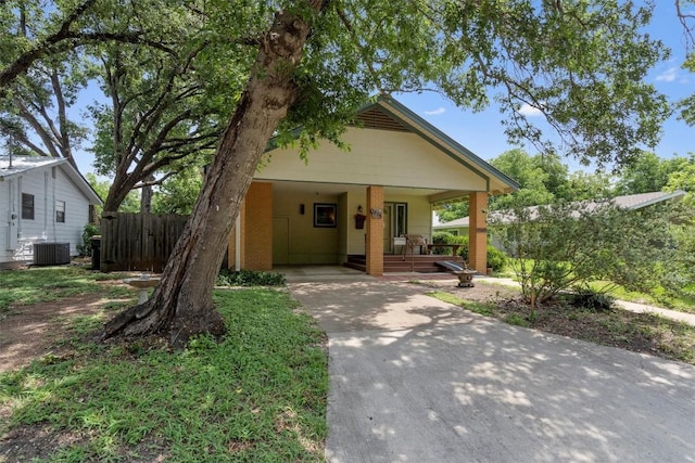 view of front facade featuring cooling unit, concrete driveway, fence, and an attached carport