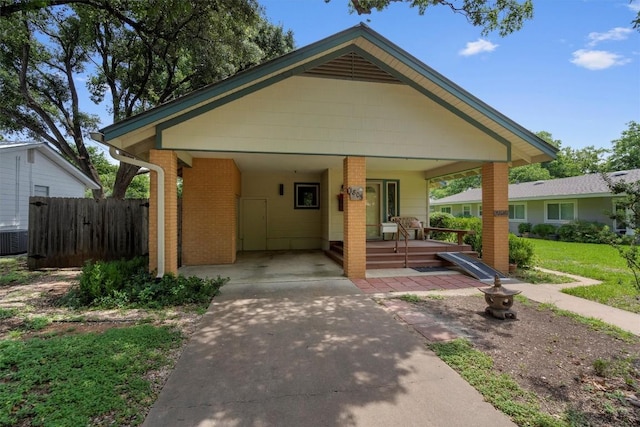 bungalow-style home with a carport, brick siding, fence, and driveway