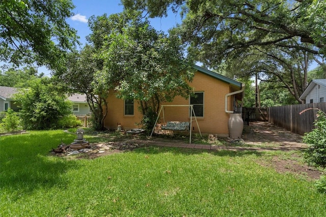 back of house with fence, a lawn, and brick siding