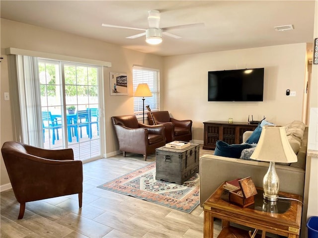 living room with visible vents, ceiling fan, and baseboards