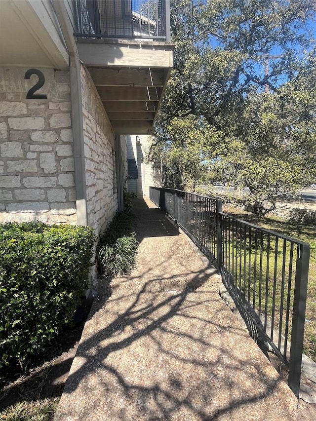 view of property exterior featuring stone siding and fence