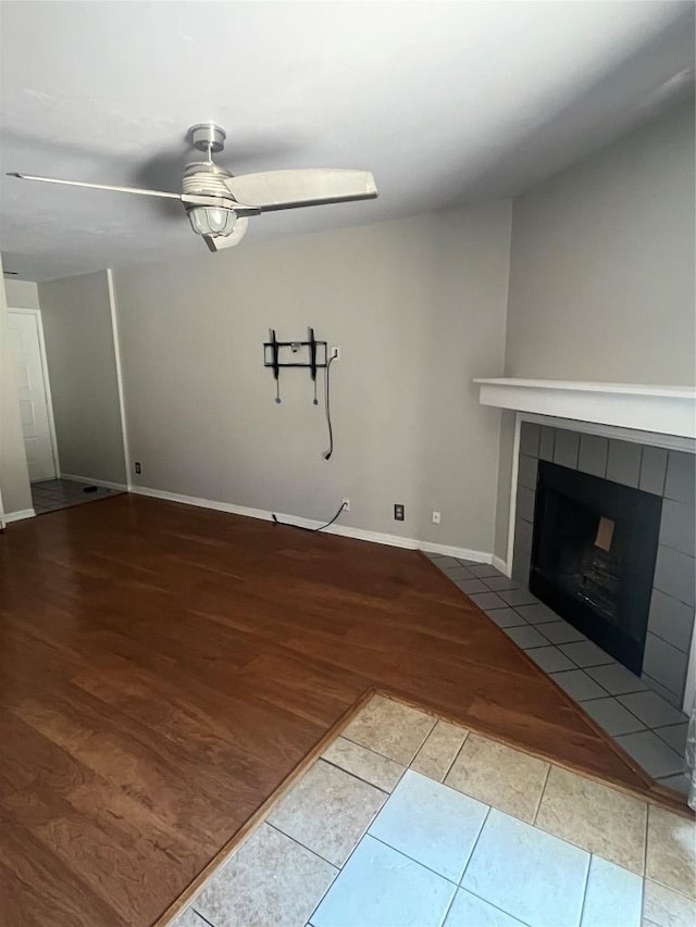 unfurnished living room with ceiling fan, a fireplace, baseboards, and wood finished floors