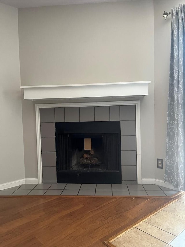 details with baseboards, a tiled fireplace, and wood finished floors