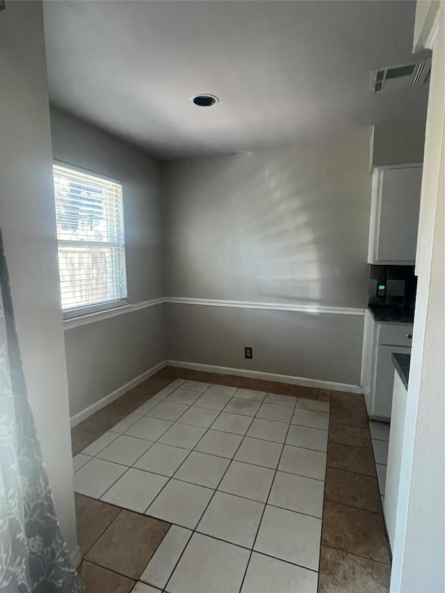 unfurnished dining area with light tile patterned flooring, visible vents, and baseboards