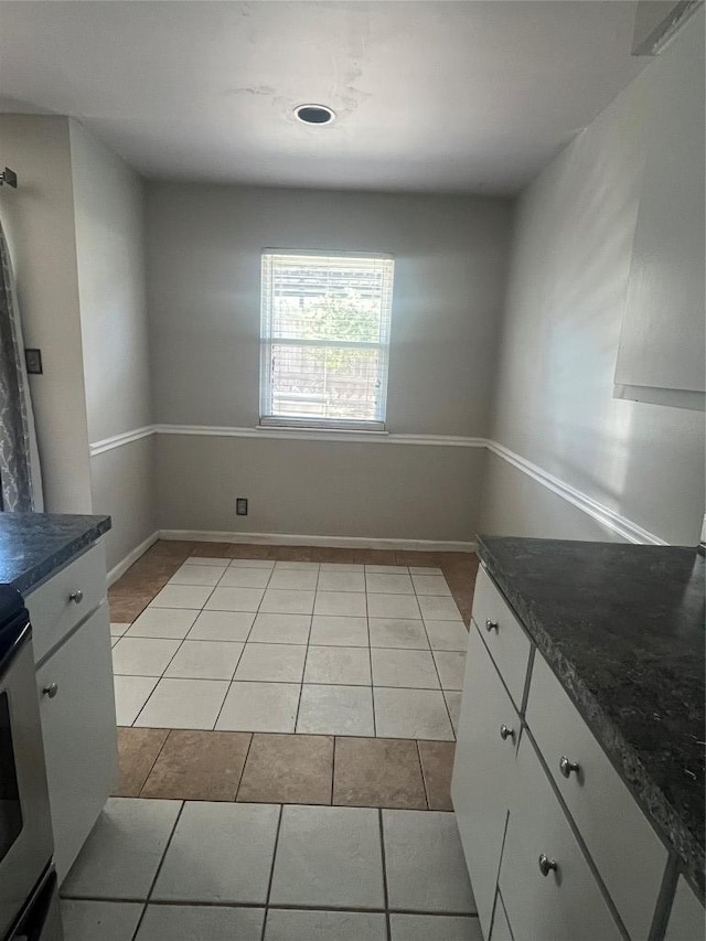 unfurnished dining area featuring light tile patterned flooring and baseboards