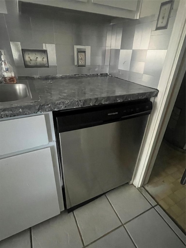 kitchen with a sink, dark stone countertops, dishwasher, and light tile patterned flooring