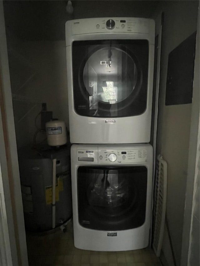 laundry area featuring laundry area, water heater, and stacked washer and clothes dryer