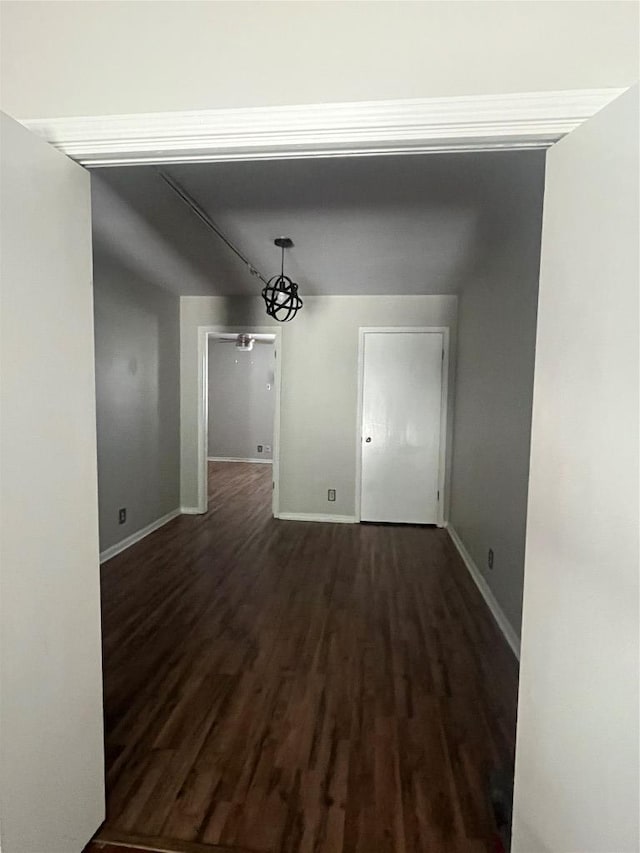 unfurnished dining area with dark wood-style floors and baseboards