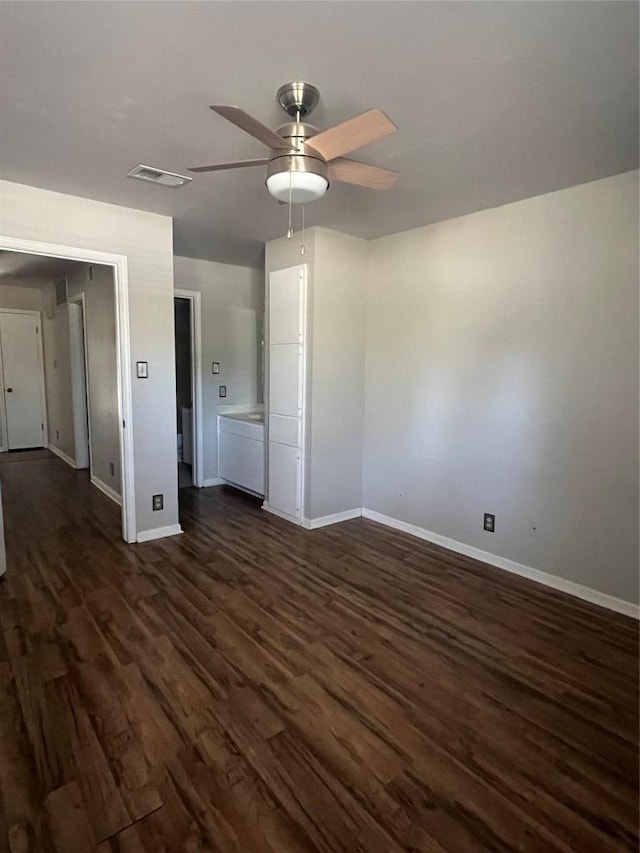 interior space featuring a ceiling fan, dark wood-style flooring, visible vents, and baseboards