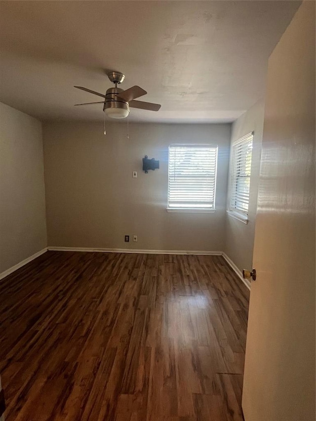 spare room with dark wood-style flooring, ceiling fan, and baseboards