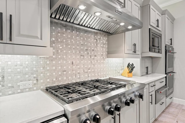 kitchen featuring light countertops, ornamental molding, appliances with stainless steel finishes, backsplash, and wall chimney exhaust hood