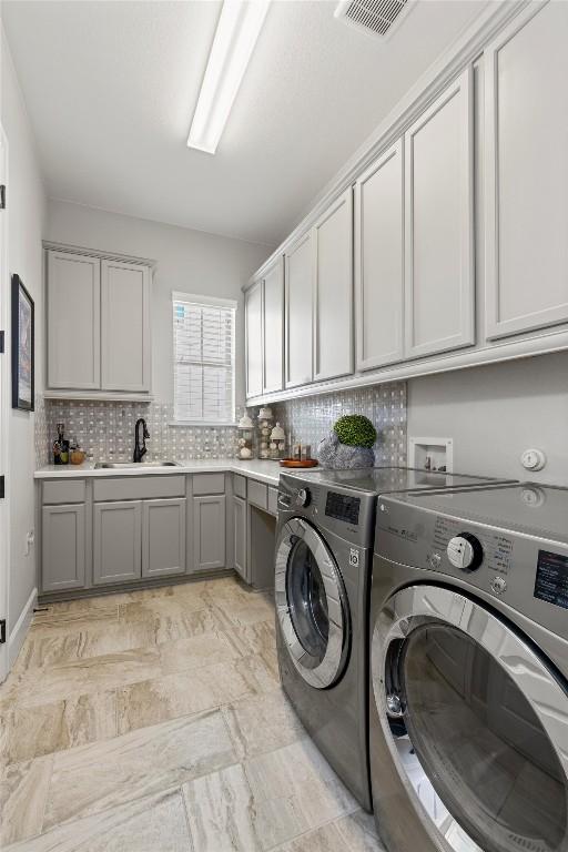 laundry area with washer and dryer, visible vents, a sink, and cabinet space