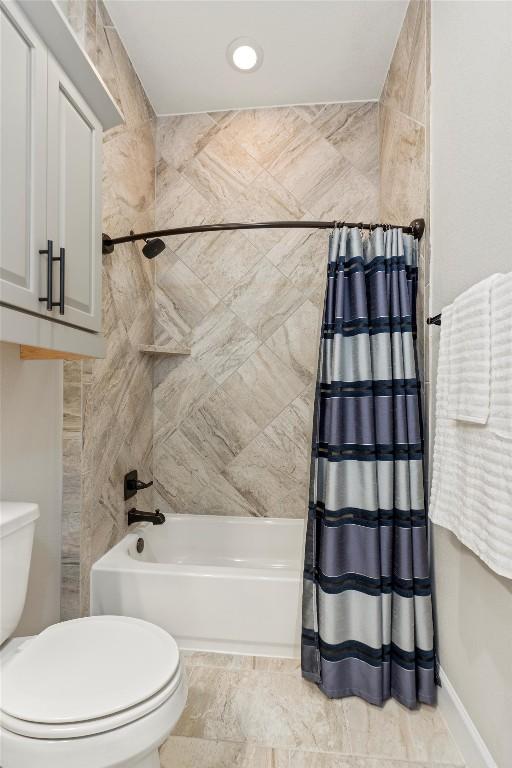 full bathroom with baseboards, shower / bathtub combination with curtain, and toilet