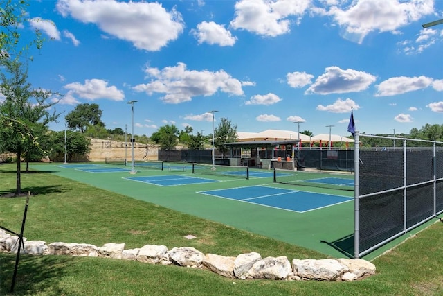 view of tennis court featuring fence and a yard