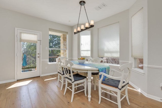 dining room featuring an inviting chandelier, light wood-style flooring, visible vents, and baseboards