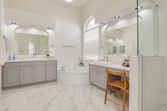 full bathroom with a garden tub, marble finish floor, a sink, and tiled shower