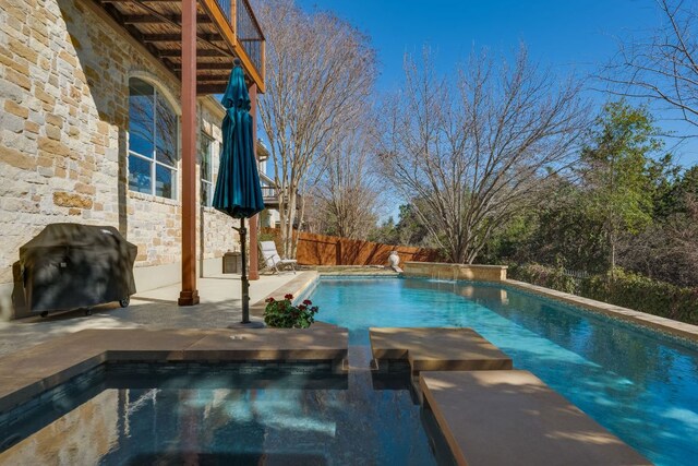 view of swimming pool with a patio, a grill, a pool with connected hot tub, and fence